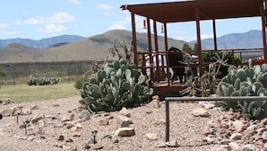 Un paysage désertique avec des cactus et une structure en bois dotée d’un toit.