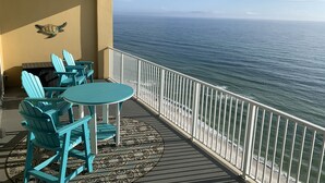 A balcony with turquoise chairs and a small table, overlooking the ocean. - Tropic Winds 1402 (Beachfront) - Free BeachService!! (Panama City Beach)