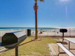 Un espace extérieur aménagé avec un barbecue, une table de pique-nique et une vue sur la plage.