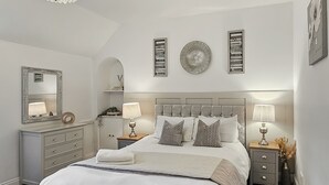 Une chambre à coucher avec un grand lit, des tables de chevet, une commode, un lustre et des éléments décoratifs sur les murs.