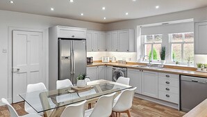 Une cuisine moderne avec une table à manger en verre, des chaises blanches, des meubles de rangement gris et un lave-vaisselle encastré.