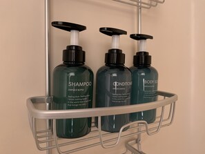 Estante de baño con tres botellas de champú, acondicionador y gel de baño.