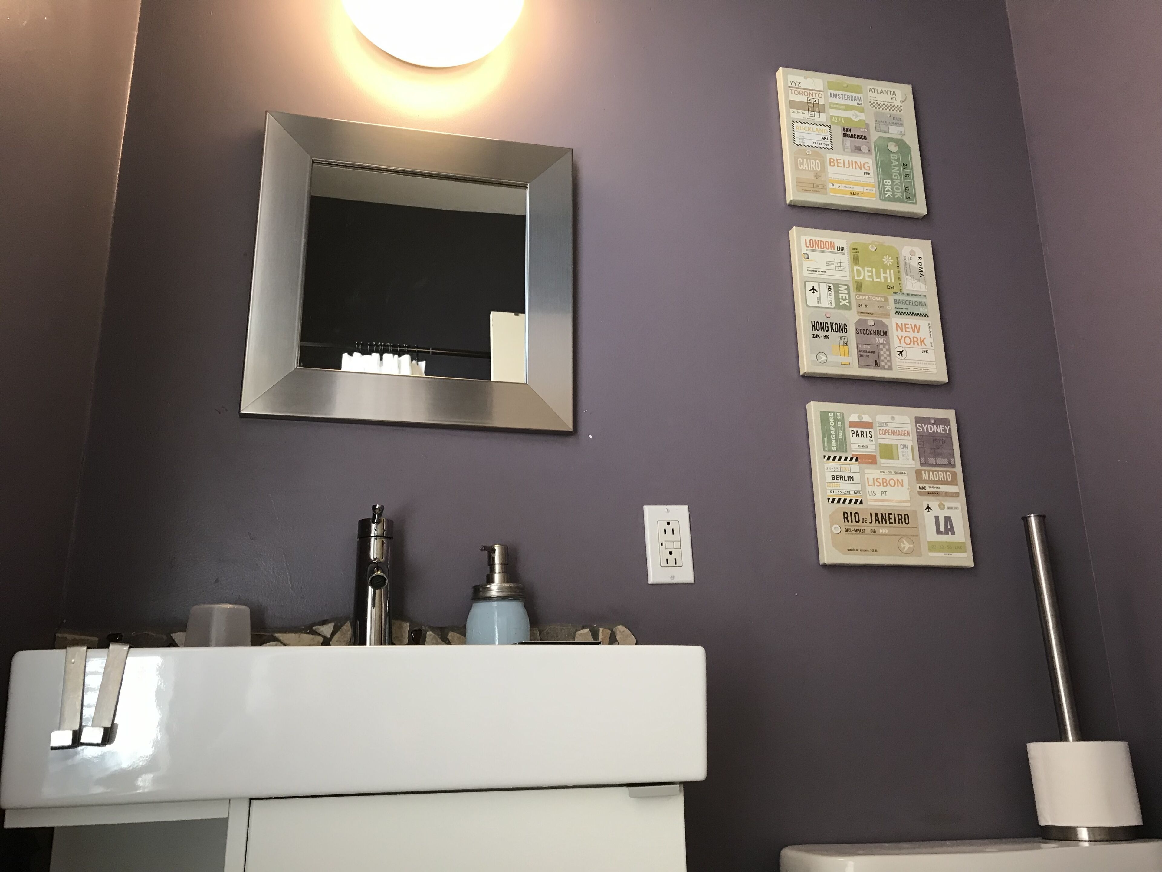 A bathroom with a mirror, sink, and toiletries. There are travel maps on the wall.