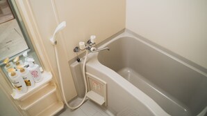 Een badkamer met een bad, een douche en een plank met toiletartikelen.