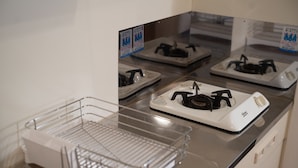 Een keuken met een rvs aanrecht, een witte kookplaat en een heldere afdruiprek.