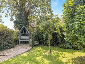 A garden with a wooden arbor, a small tree, and dense shrubbery. - 4 bedroom accommodation in Hogsthorpe, near Skegness (Hogsthorpe, near Skegness)