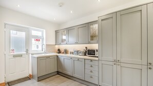 A modern kitchen with grey cabinets, a stainless steel sink, and a microwave. - 4 bedroom accommodation in Hogsthorpe, near Skegness (Hogsthorpe, near Skegness)