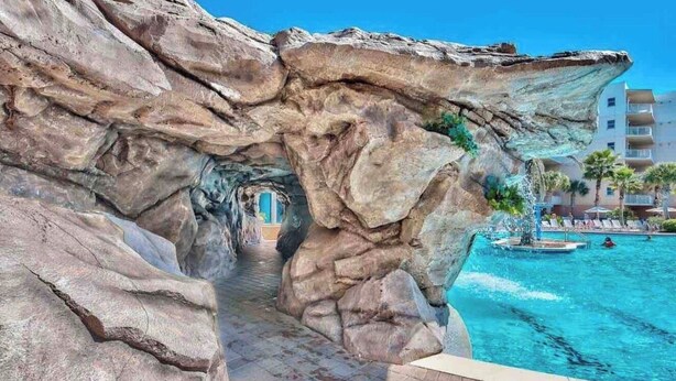 A rock formation leading to a pool area with a clear view of a building in the background. - Ground floor easy access! A127 (Fort Walton Beach)