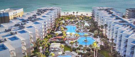 A resort with multiple swimming pools, palm trees, and beachfront views.