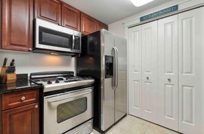 A kitchen with a stove, oven, microwave, refrigerator, and wooden cabinets. - Ground floor easy access! A127 (Fort Walton Beach)