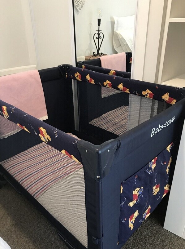 A baby crib with a Winnie the Pooh theme, a black metal frame, and a mesh bottom.