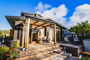 A modern house with a covered patio, wooden steps, and outdoor furniture.