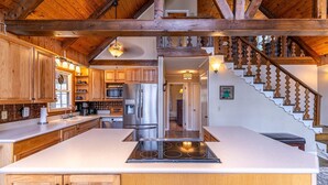Una cocina con armarios de madera, un refrigerador de acero inoxidable, un microondas y una isla grande con estufa.