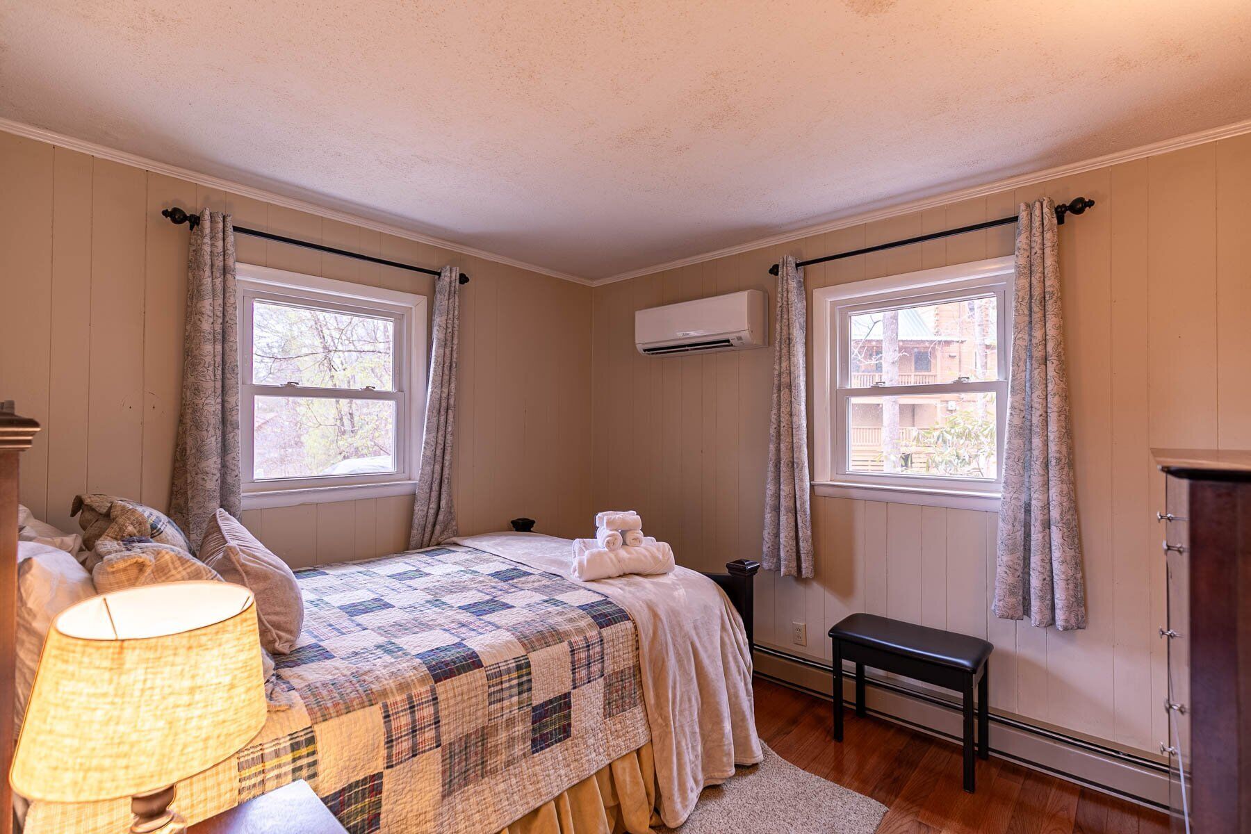 Fresh towels waiting on a cozy patchwork quilt, plenty of natural light, and your own climate control for a restful night.