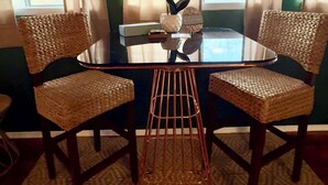 Une table ronde en verre, des chaises en osier, un vase rempli de fleurs roses et une pancarte indiquant « Bienvenue ».
