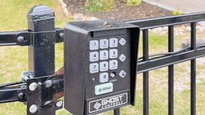 Un clavier de sécurité noir doté d’un bouton « ENVOYER », fixé sur un poteau métallique à l’aide de vis.