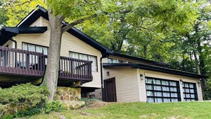 Une maison à deux étages avec des fondations en pierre, un balcon et un garage.