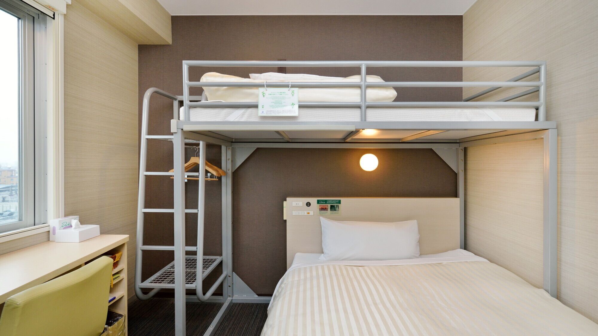A bunk bed room with a desk, a chair, and a window.