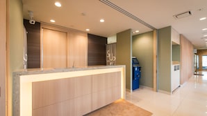 Un espace d’accueil d’hôtel comprenant un comptoir, un kiosque numérique et une salle de bain avec douche.