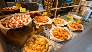 Un buffet proposant une vari été de produits de boulangerie, notamment du pain, des croissants et des viennoiseries.