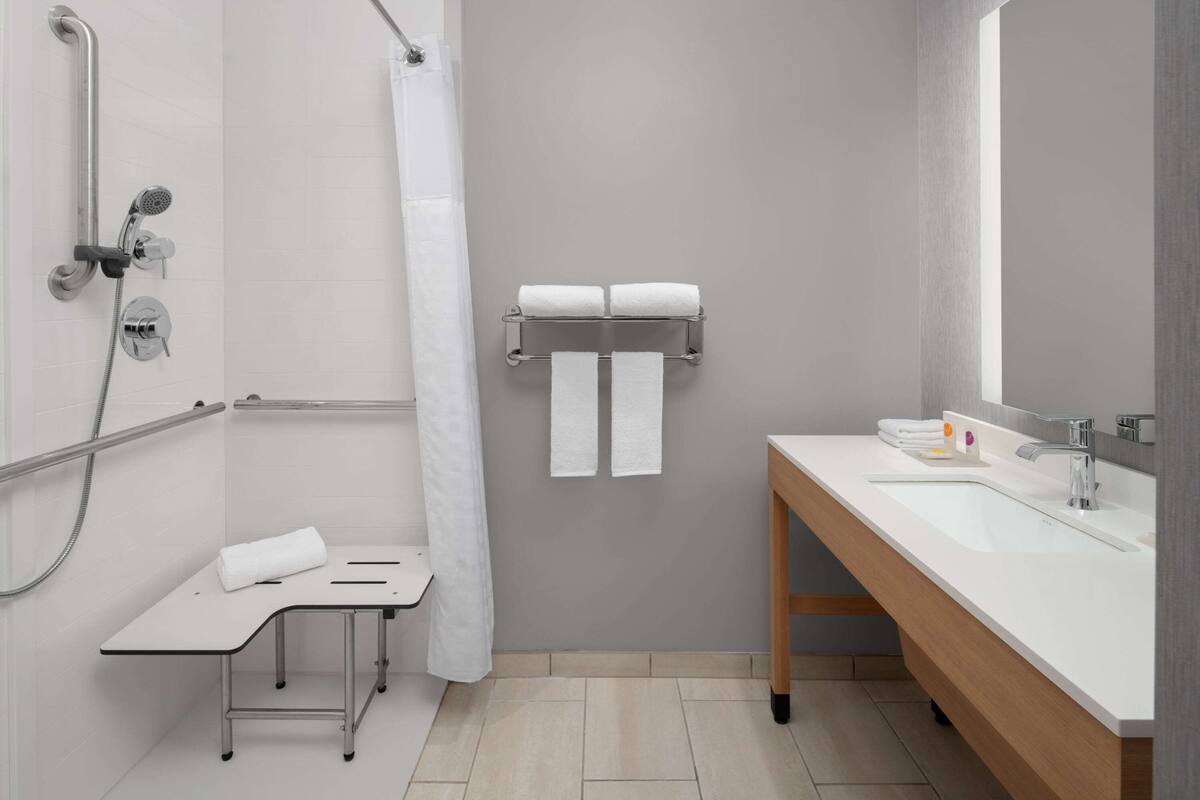 A modern bathroom with a shower, a sink, and a towel rack.