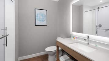 A modern bathroom with a white sink, a large mirror, and a toilet.