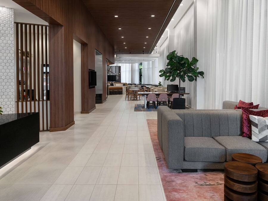 Eine moderne Hotelhalle mit Rezeption, Sitzgelegenheiten und einer großen Pflanze.