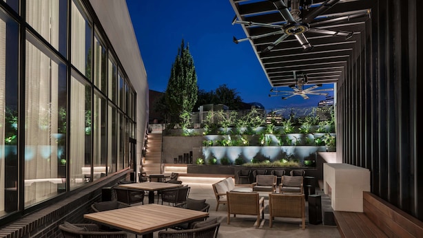 An outdoor seating area with tables and chairs, a water feature, and a staircase leading to an upper level. - Hyatt Place Atlanta / Perimeter Center (Atlanta)