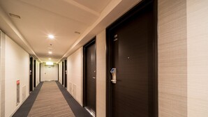A hotel corridor with carpeted floors, dark wooden doors, and a light-colored wall. - Super Hotel Ube Kosan Street (Ube)