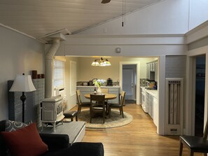 Relax in this open-plan living space with a dining table, sofa, and kitchen area featuring a stove, refrigerator, and sink.