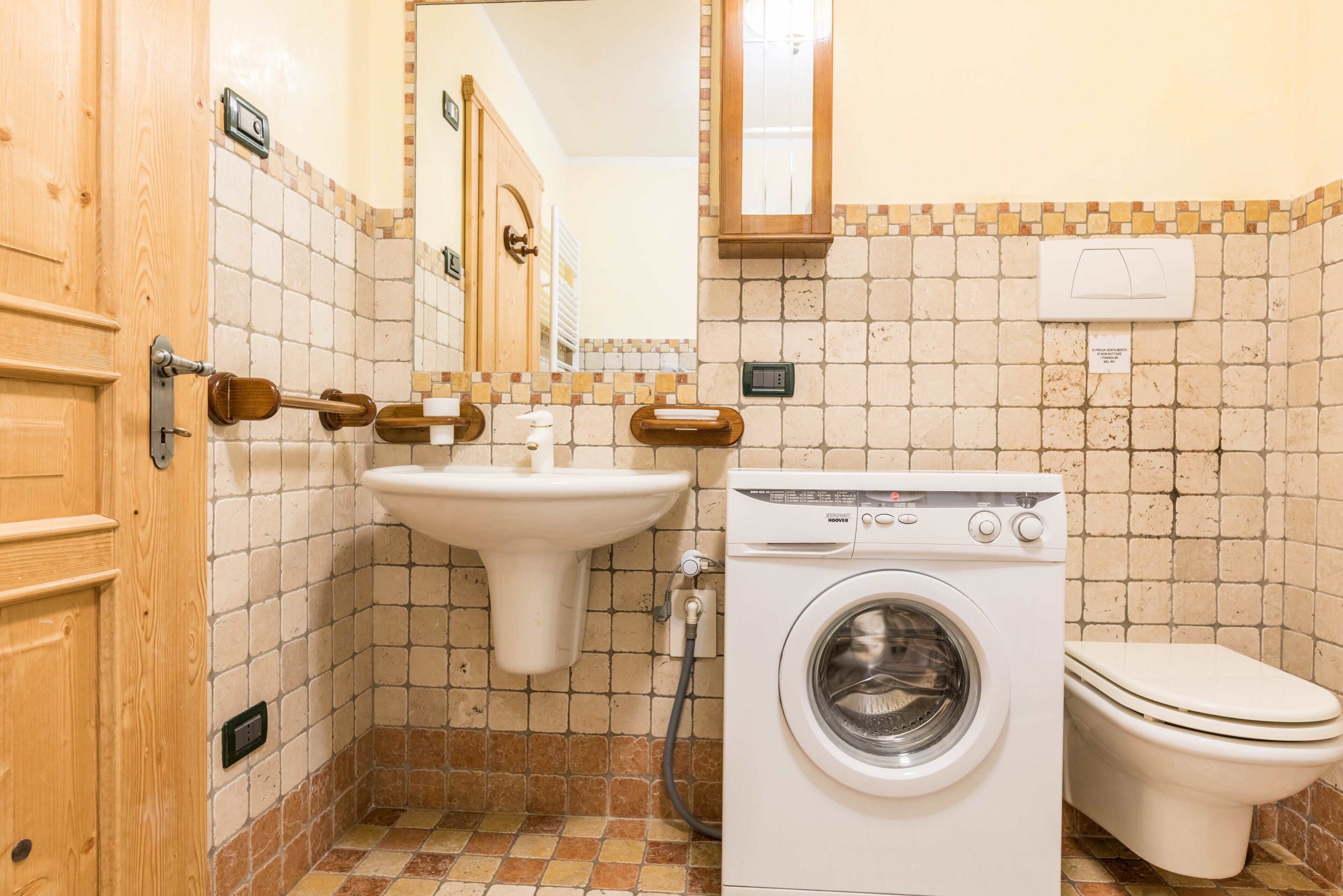 A bathroom with a sink, toilet, and washing machine.