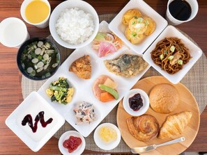 Une variété de plats, notamment du riz, de la soupe et des pâtisseries, sont disposés sur une table en bois.