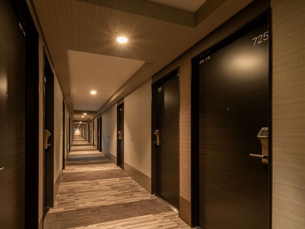 A hotel corridor with wooden doors numbered 725 and 723, carpeted floors, and recessed lighting.