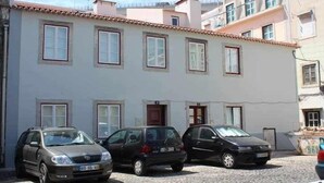 Tres coches están estacionados frente a un edificio con muchas ventanas y techo de tejas.
