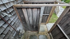 A wooden shed with a slanted roof, a door, and a small step leading up to it.