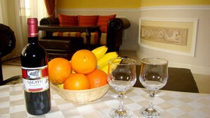 A dining table with a bottle of wine, a basket of oranges, and two empty wine glasses. - Luxury Apartment Venice - 1 (Sofia)