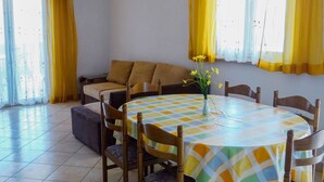 A dining area with a round table covered by a checkered tablecloth, surrounded by wooden chairs. - Beautiful Coastline View Apartment a4 (Pag)