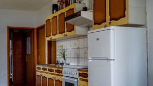 A kitchen with wooden cabinets, a white refrigerator, a stove, and a tiled backsplash. - Beautiful Coastline View Apartment a4 (Pag)