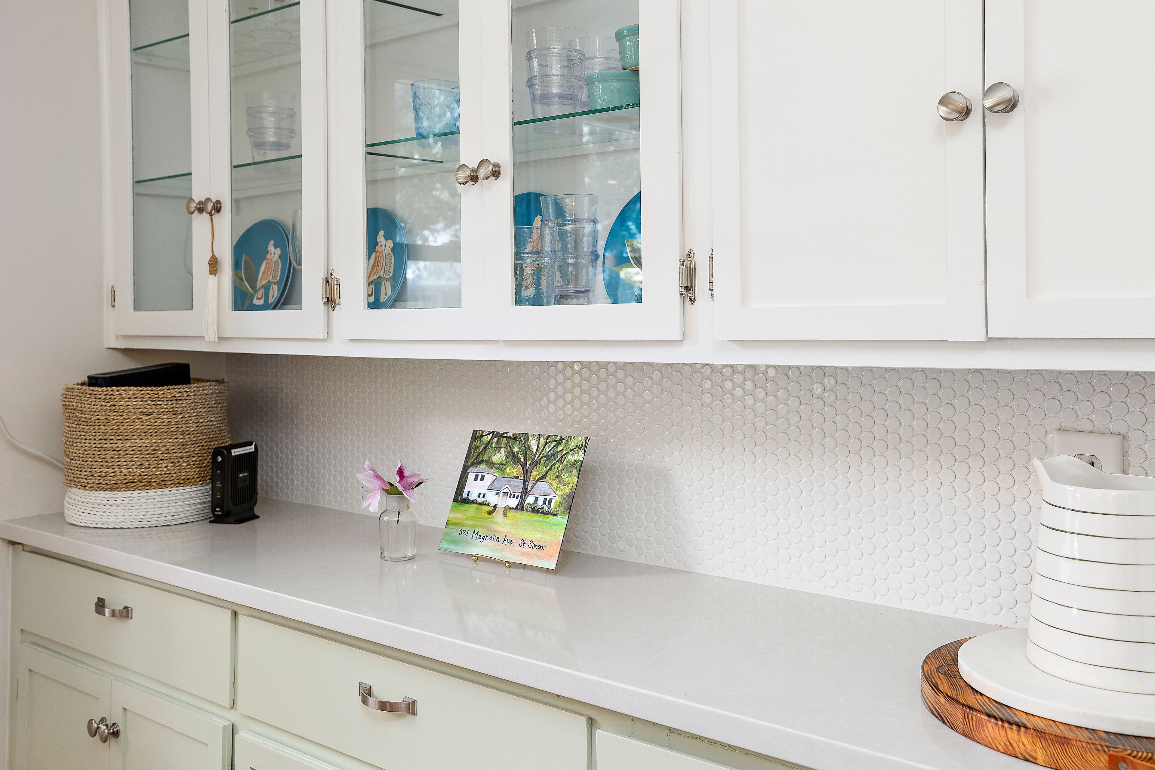 A kitchen with white cabinets, a white countertop, and a decorative plate.