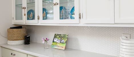 A kitchen with white cabinets, a white countertop, and a decorative plate.