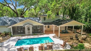 Ein Haus mit Swimmingpool, überdachter Terrasse und einem eingezäunten Garten.