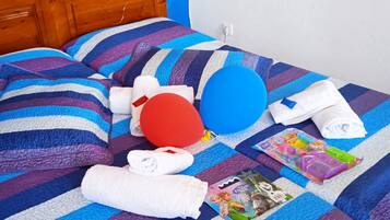 Cozy retreat with a neatly made bed, featuring a striped bedspread and two pillows, a towel, and a colorful toy set.