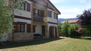 A two-story house with a stone facade, a balcony, and a grassy yard.