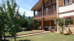 A two-story building with a balcony, outdoor seating, and a garden area.