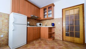 Een keuken met houten kastjes, een witte koelkast, een magnetron en een fornuis.