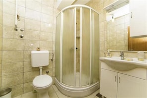 A bathroom with a toilet, a shower enclosure, a sink, and a mirror.