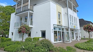 Un immeuble de deux étages doté d’un balcon, d’une devanture de magasin et d’une enseigne sur laquelle on peut lire « FEWO&MEER ».