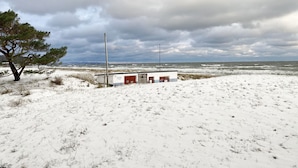 Un paysage enneigé avec un bâtiment doté d’une porte rouge et d’une petite construction adjacente.