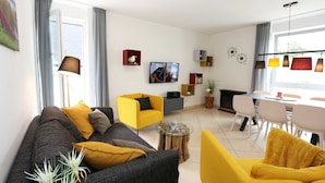 Un salon moderne avec un canapé, un fauteuil jaune et une table basse.