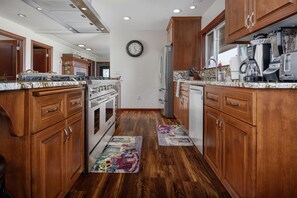 Una cocina con armarios de madera, electrodomésticos de acero inoxidable y un reloj en la pared.